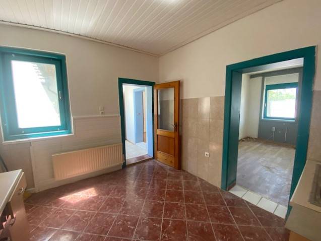 A room with windows and doors, a light ceiling and tiles, apartment construction.