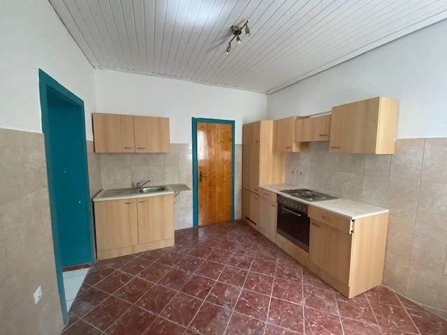A kitchen with wooden cabinets, a sink, and a stove in apartment construction.