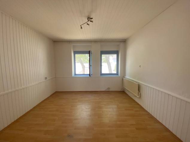 A spacious room with wooden flooring, white walls, and two windows, Apartment construction.