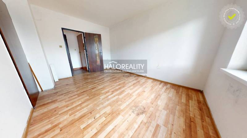 A spacious room with wooden flooring in a 3-room apartment, bright walls, and a large window.