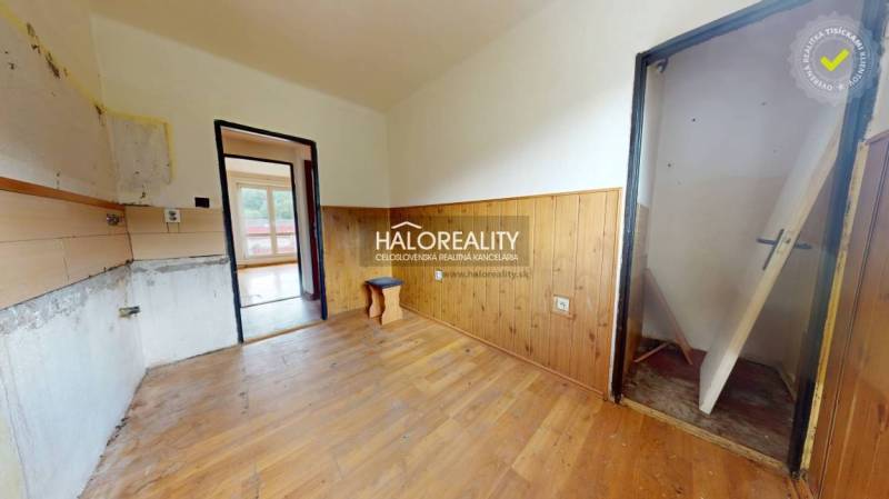 A room in a 3-room apartment with wooden paneling and empty walls for renovation.