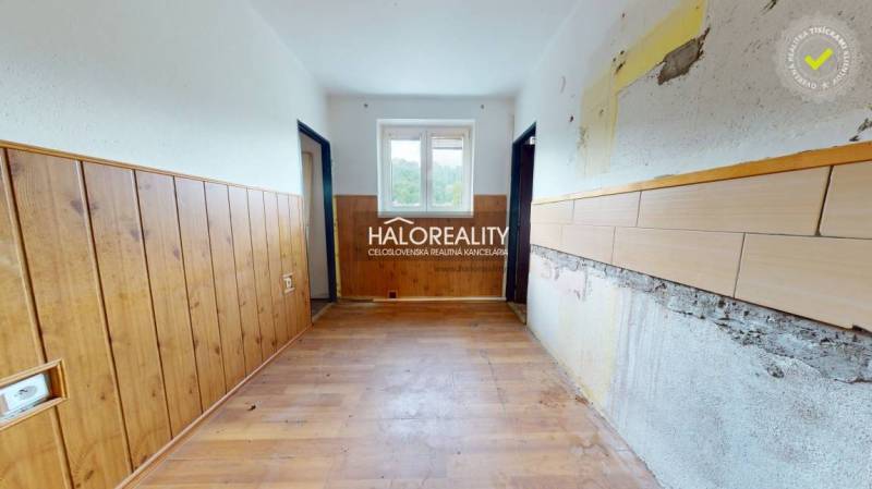 A hallway of a 3-room apartment with older wooden paneling and a window.