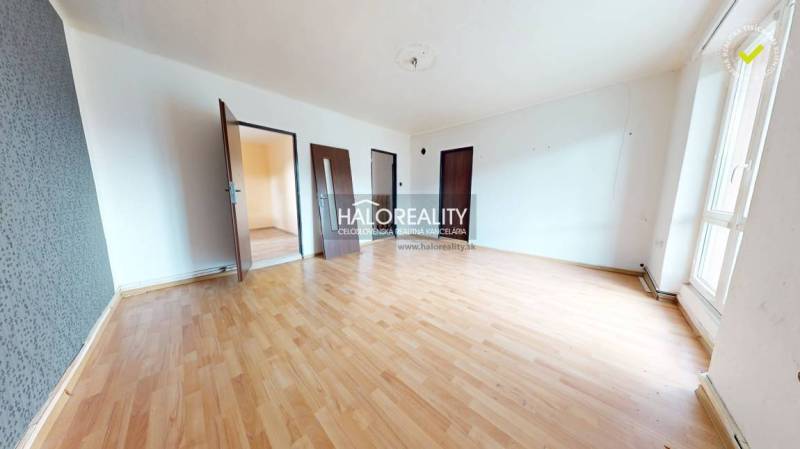 A spacious room with wooden flooring and multiple doors in a 3-room apartment.