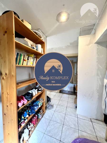 A hallway in a family house with a shoe rack and books on a shelf.
