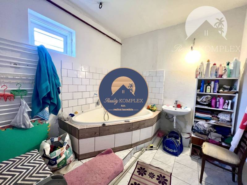 A bathroom in a family house with a bathtub, a sink, and a shelf with toiletries.