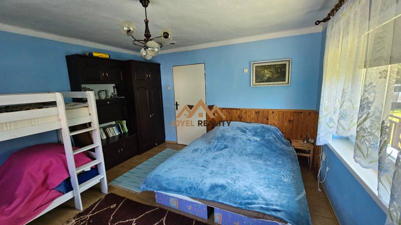 Blue room with a bunk bed, double bed, and dark wardrobe in a family house.