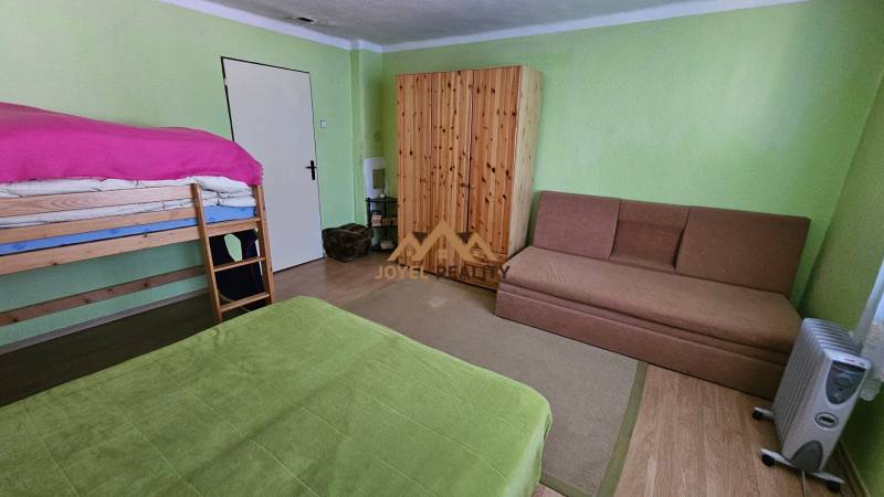 A room in a family house with a bunk bed, a sofa, and a built-in wardrobe.