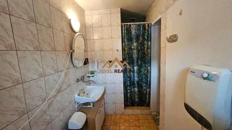 Bathroom in a family house with a sink, shower, and tiled walls.