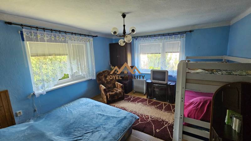 Blue room in a family house with a bed, bunk bed, television, and an armchair.