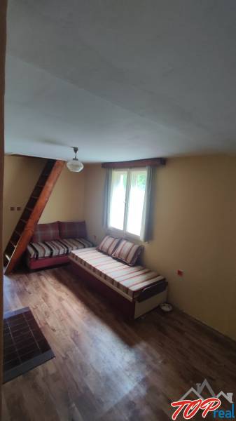 Living room in a cabin with wooden flooring, a sofa, and a staircase.