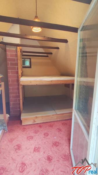 Attic room in a cabin with a bunk bed and a red carpet.