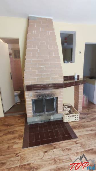 Interior in a cabin with a fireplace, parquet flooring, and entrance to the bathroom.