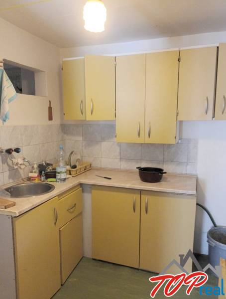 A kitchen in a cottage with double-door cabinets, a sink, and a gas connection.