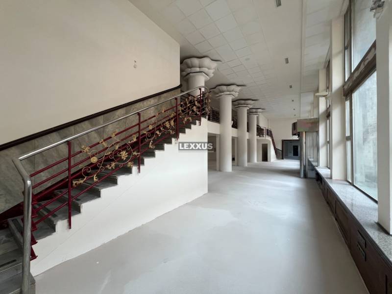 Spacious commercial spaces with a staircase and decorative railing, large windows.