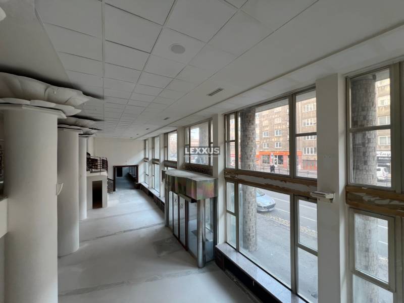 Commercial spaces with large windows and massive columns, offering a view of the street.