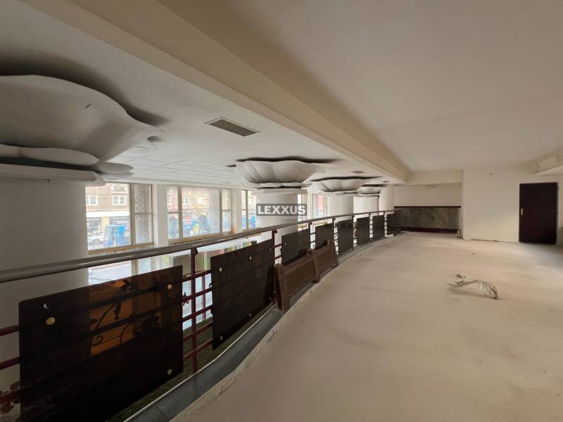 Interior of commercial spaces with large windows and railing on the upper floor.
