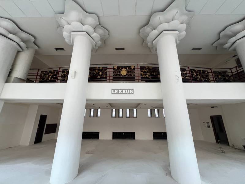Interior of commercial spaces with large columns and decorative railing on the upper floor.