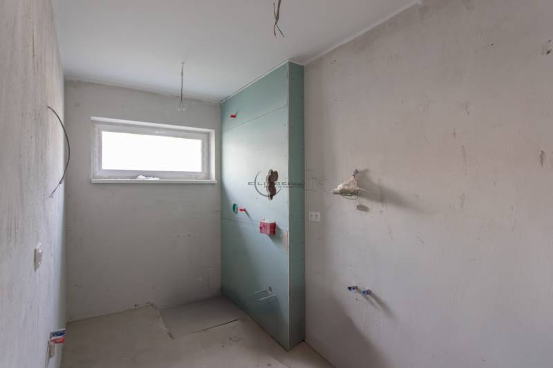 Unfinished bathroom in a 2-room apartment with a window and preparation for installations.