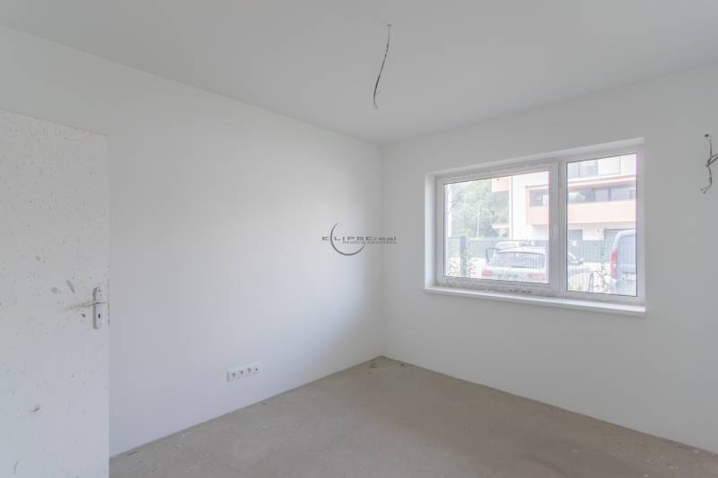 An unfurnished room with light walls and a large window in a 2-room apartment.