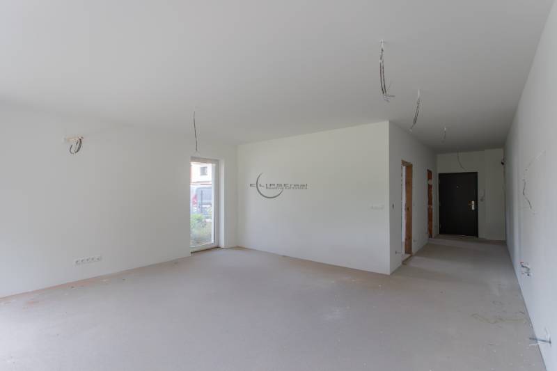 A spacious room in a 2-room apartment with bare walls and prepared electrical wiring.
