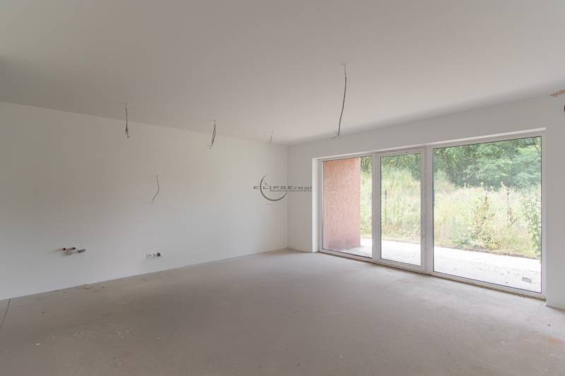 Empty room in a 2-room apartment with panoramic windows and a view of greenery.
