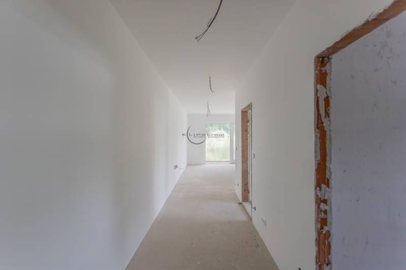 A spacious hallway in a 2-room apartment with bare walls and unfinished surfaces.