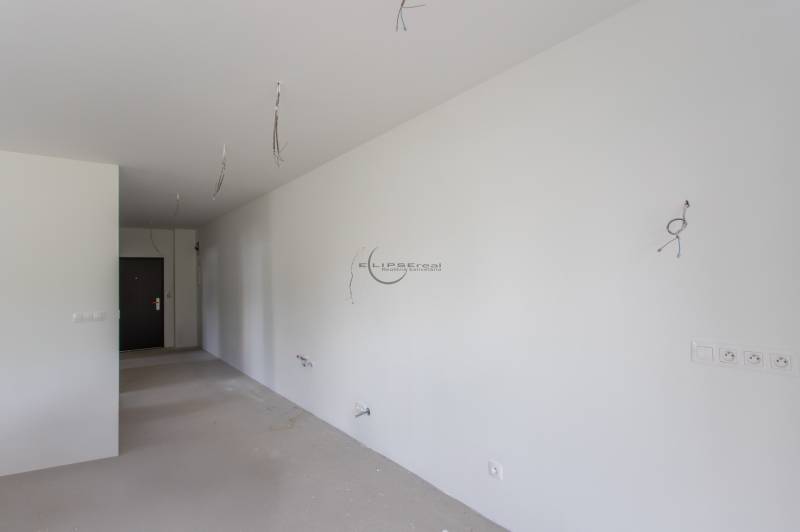 An unfurnished room in a 2-room apartment with white walls and cables.