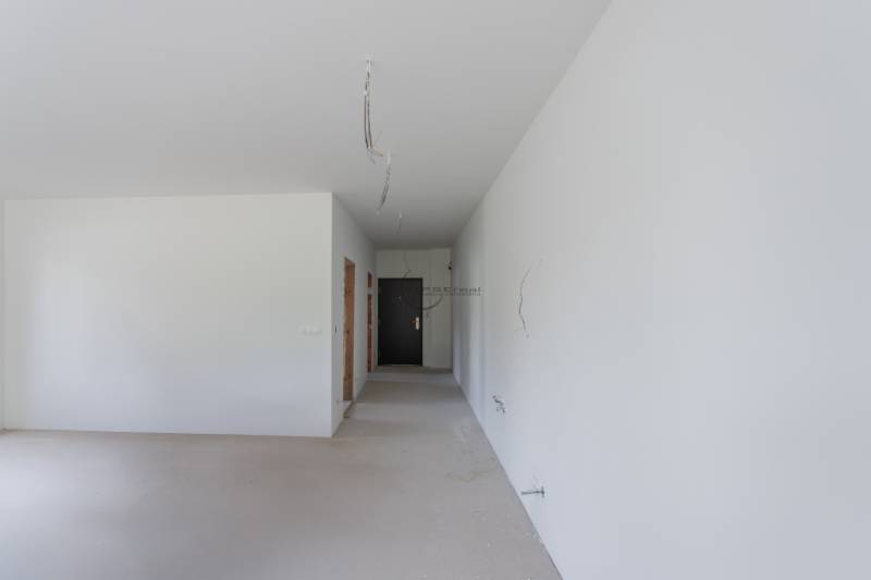 An empty room with white walls in a 2-room apartment, electrical wires hanging from the ceiling.