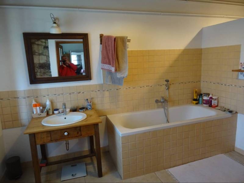 A bathroom in a family house with a bathtub, mirror, and wooden sink.
