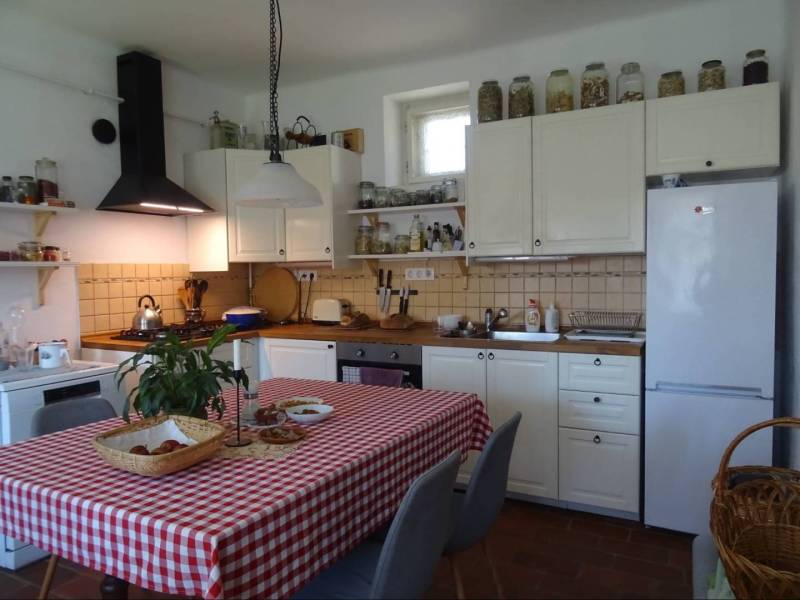 A family house kitchen with wooden furniture, a checkered tablecloth, and kitchen appliances.