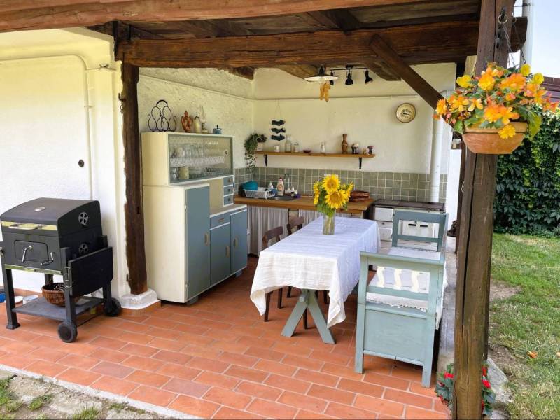 In the summer kitchen of a family house in Pányok, there is a terrace with a table, chairs, a grill, and flowers.