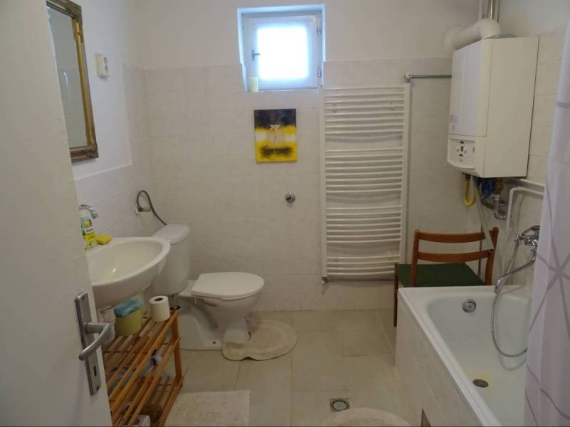 Bathroom of a family house with a bathtub, sink, toilet, and mirror.