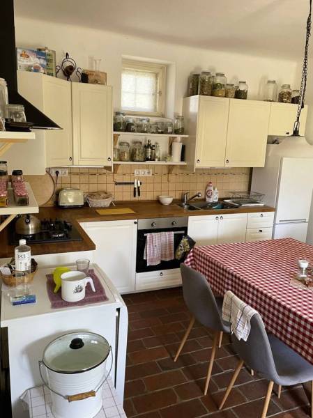 A kitchen in a family house with white cabinets and a checkered tablecloth on the table.