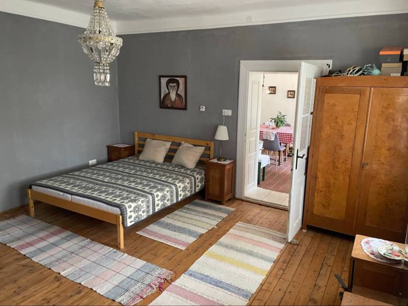 Bedroom in a family house with a wooden bed and dresser, leading to the dining room.