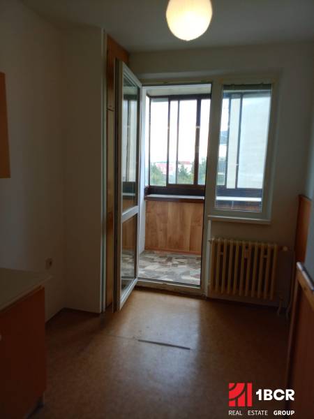 Windows with a balcony and a radiator in a 3-room apartment, simple flooring.