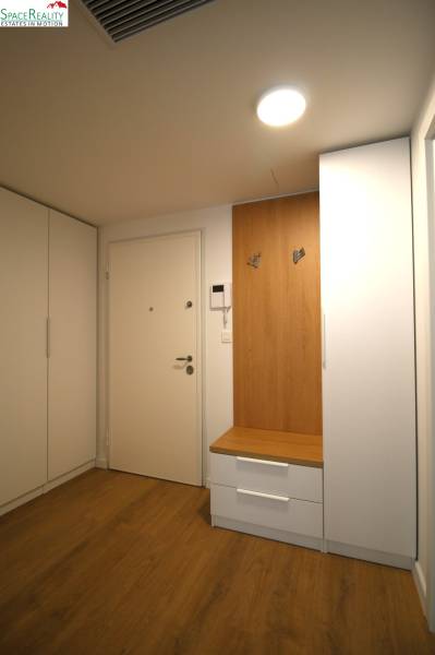 Hallway in a 2-room apartment with white cabinets and a wooden coat rack.