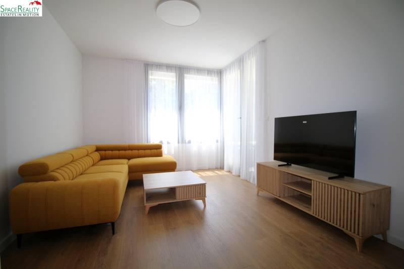 Living room with a large yellow sofa and a television in a two-room apartment.
