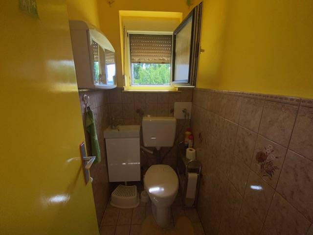 Yellow bathroom in a family house with a sink, toilet, and window.