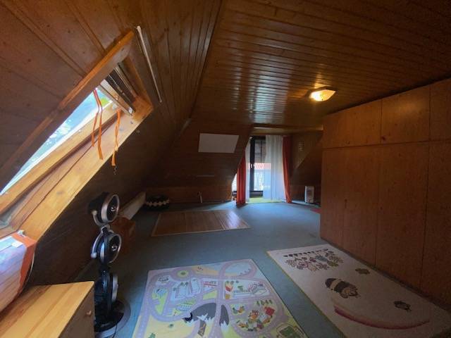 An attic room in a family house with wooden paneling and carpets.