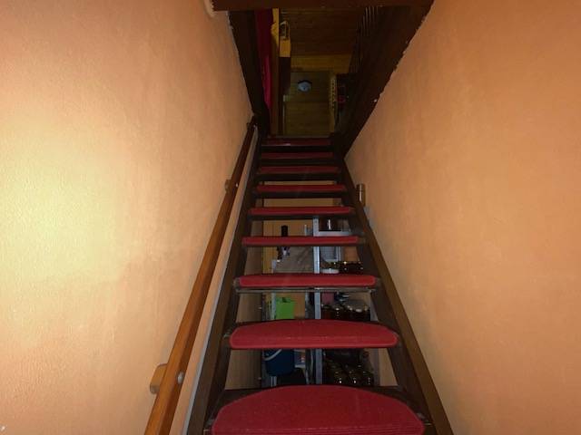 Stairs with red carpets in the interior of a family house with orange walls.