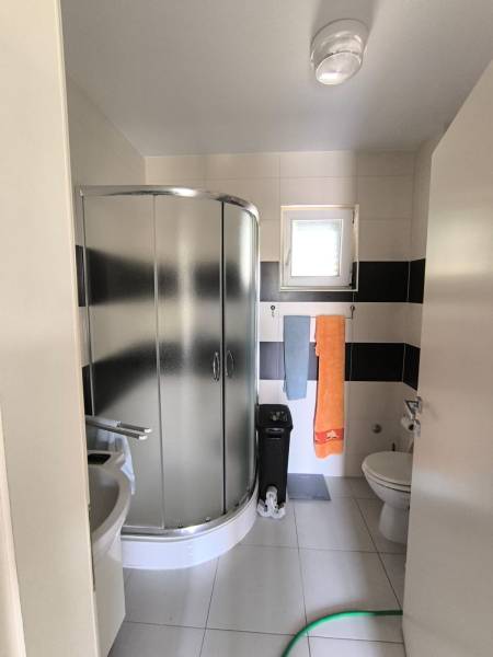 Compact bathroom with a shower, sink, and toilet in a 2-room apartment.
