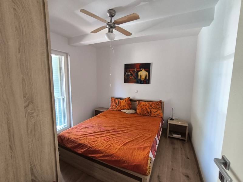 Bedroom in a 2-room apartment with a double bed, ceiling fan, and table.