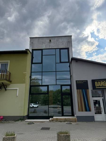Commercial premises in Poprad with modern large glass windows under a cloudy sky.