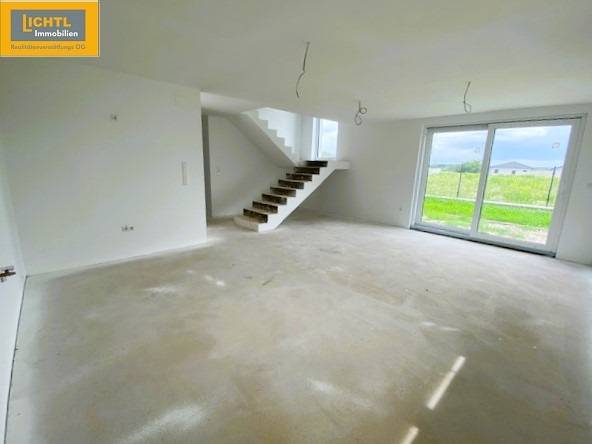 A spacious living room in a 5 or more bedroom apartment with large windows and a staircase.