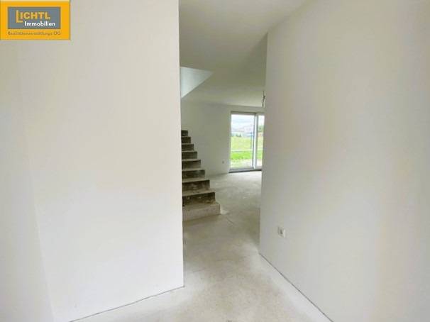 A staircase leading to a bright room in a 5 or more bedroom apartment with a view of greenery.