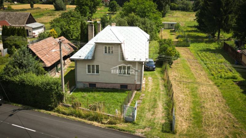 Family house in Konská with a grassy garden, access road, and surrounding nature.