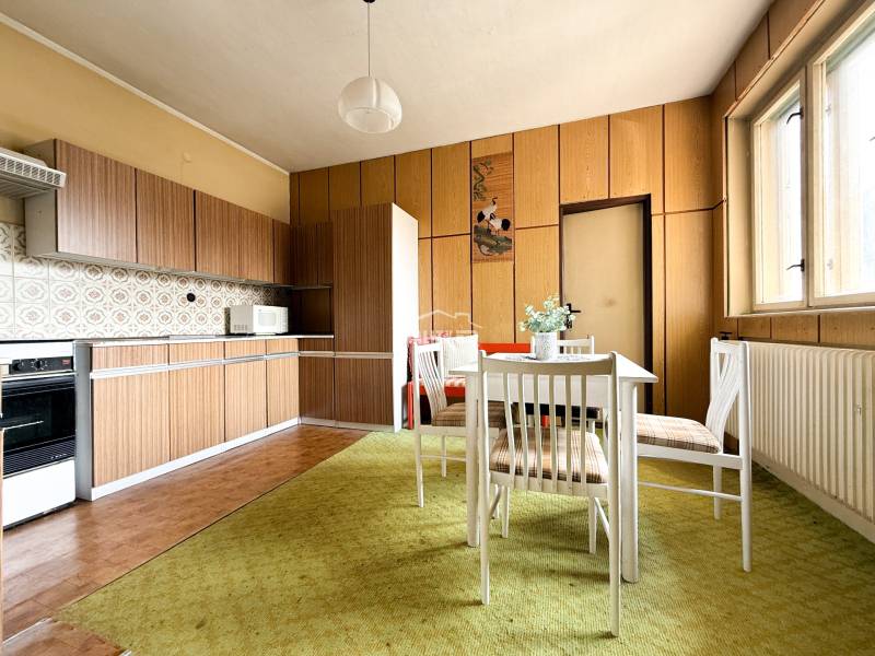 A kitchen in a family house with older furniture, a white table, and a microwave.