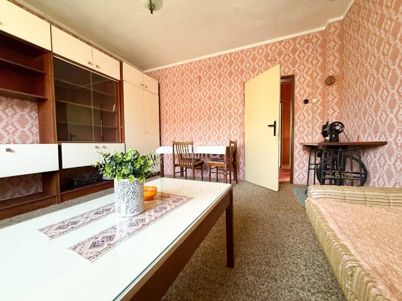 Living room with retro wallpaper, wooden furniture, and a sewing machine in a family house.