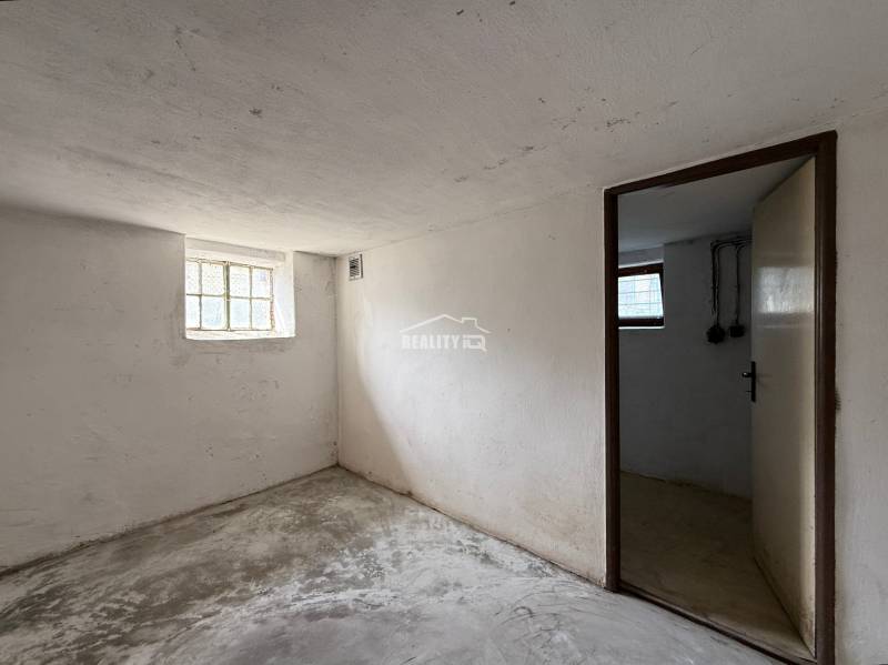 Basement room in a family house with simple interior design, concrete floor, small window.