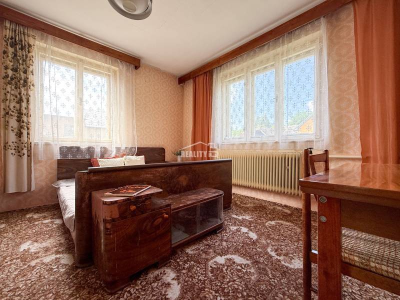 A room in a family house with carpets, windows with curtains, and wooden furniture.